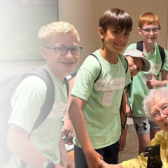 Group of Serve Camp children posing with a senior in a memory care community